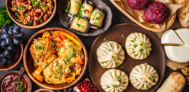 Traditional Georgian cuisine background. Khinkali, phali, chahokhbili, lobio, cheese, eggplant rolls on dark background, top view.